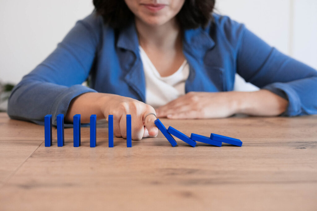 Chiara ferma con il dito le tessere di un domino blu che stanno cadendo