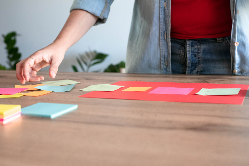 una mano muove post it come metafora di organizzare il lavoro quotidiano