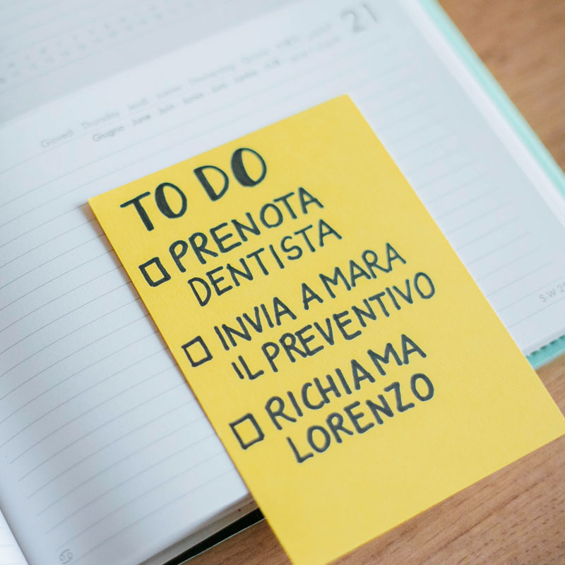 Una lista to do su cartoncino giallo con tre voci: prenota il dentista, invia a Mara il preventivo, richiama Lorenzo